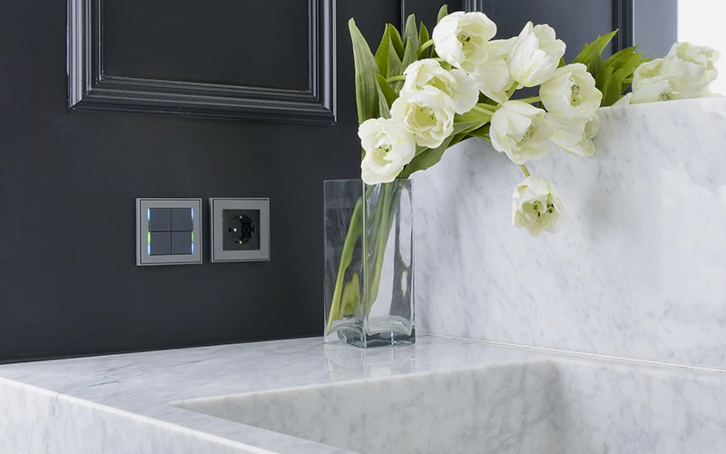 Commandes Ekinex sur un mur sombre, plan de toilette en marbre